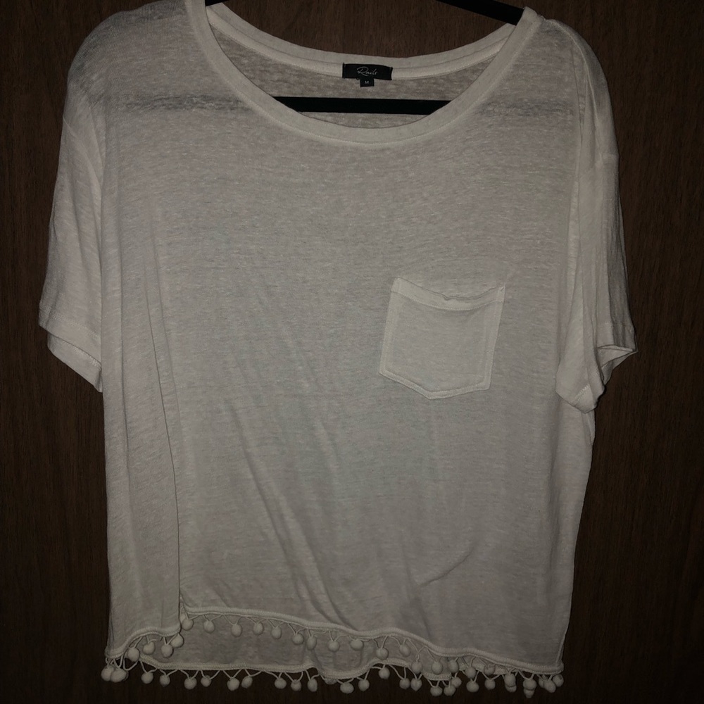 white tshirt with pom poms on the bottom